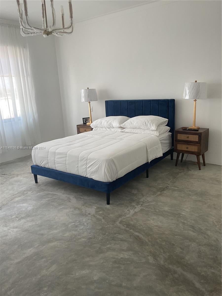 A bedroom features a blue upholstered bed, two wooden nightstands, and a polished concrete floor — 3 SW Calle el sol, Re, Re