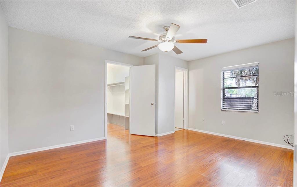 A bedroom with light gray walls, wood flooring, a ceiling fan, and an open closet — 6319 S CHURCH AVENUE, TAMPA, FL