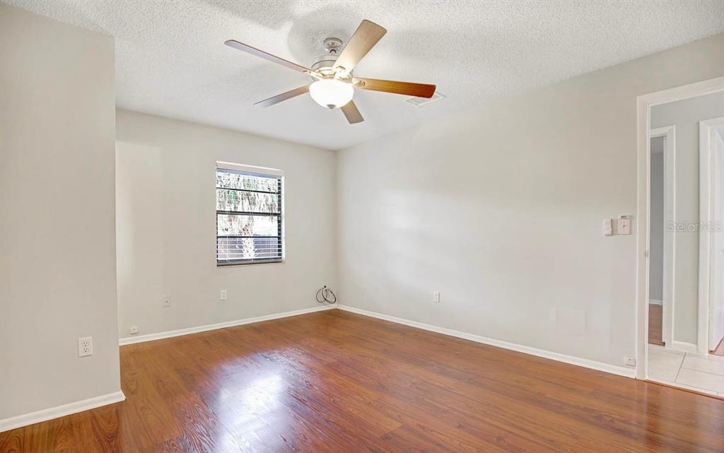 An empty bedroom features light gray walls, wood-look flooring, and a ceiling fan — 6319 S CHURCH AVENUE, TAMPA, FL