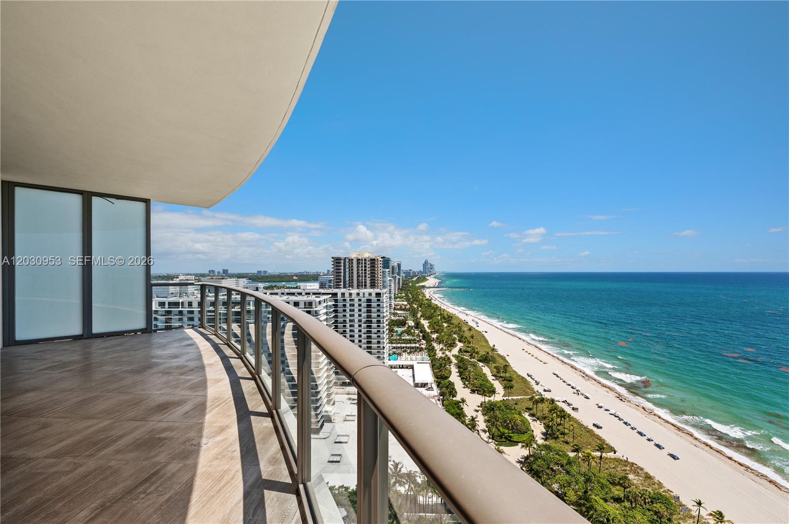 A curved balcony with glass railings overlooks a sandy beach and the ocean — 9703 Collins Ave # 2000, Bal Harbour FL 33154, BAL HARBOUR, FL