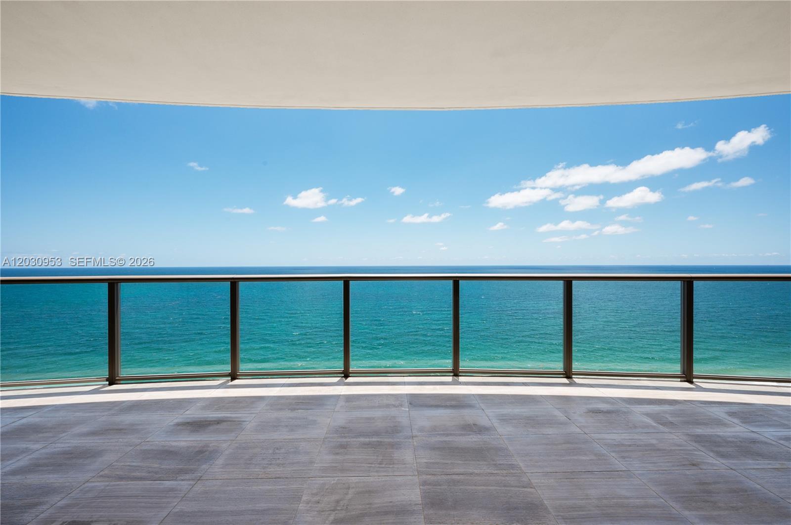 A balcony with tiled flooring and a glass railing overlooks the ocean under a blue sky — 9703 Collins Ave # 2000, Bal Harbour FL 33154, BAL HARBOUR, FL