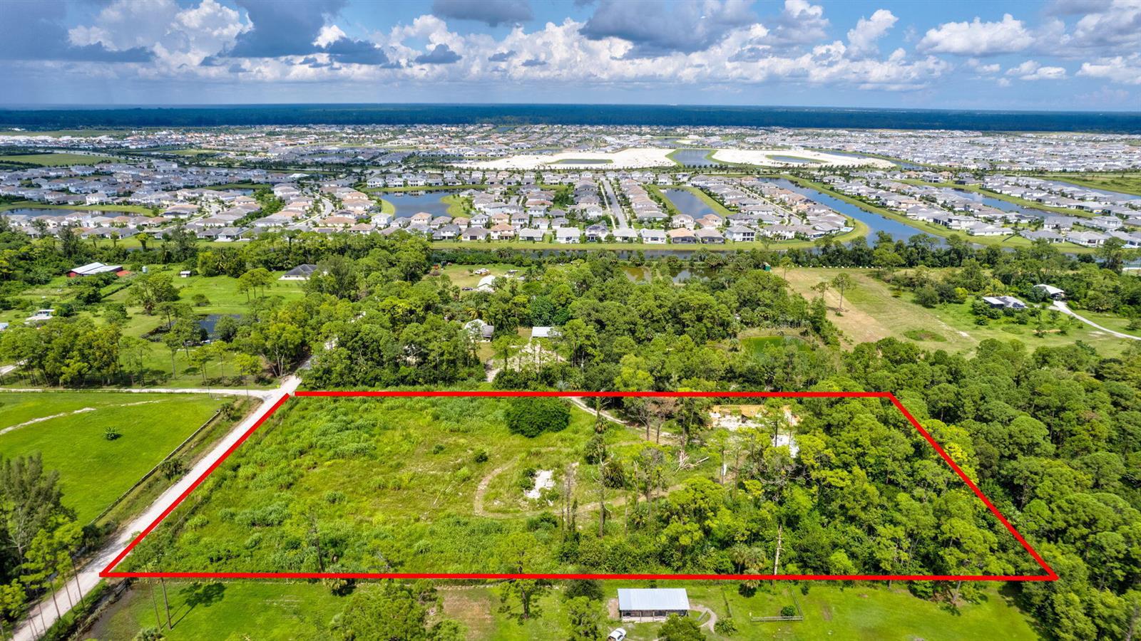 An aerial view shows a large, rectangular, undeveloped plot of land outlined in red — 15532 43rd Road N, FL 33470, FL