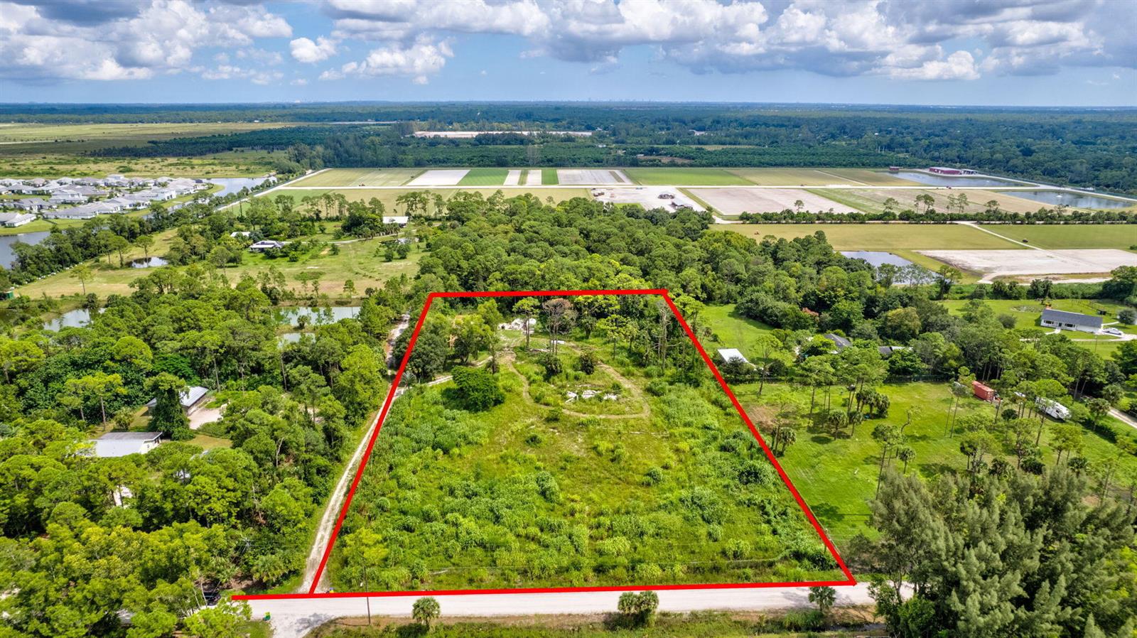 An aerial view shows a rectangular, undeveloped grassy lot outlined in red along a road — 15532 43rd Road N, FL 33470, FL