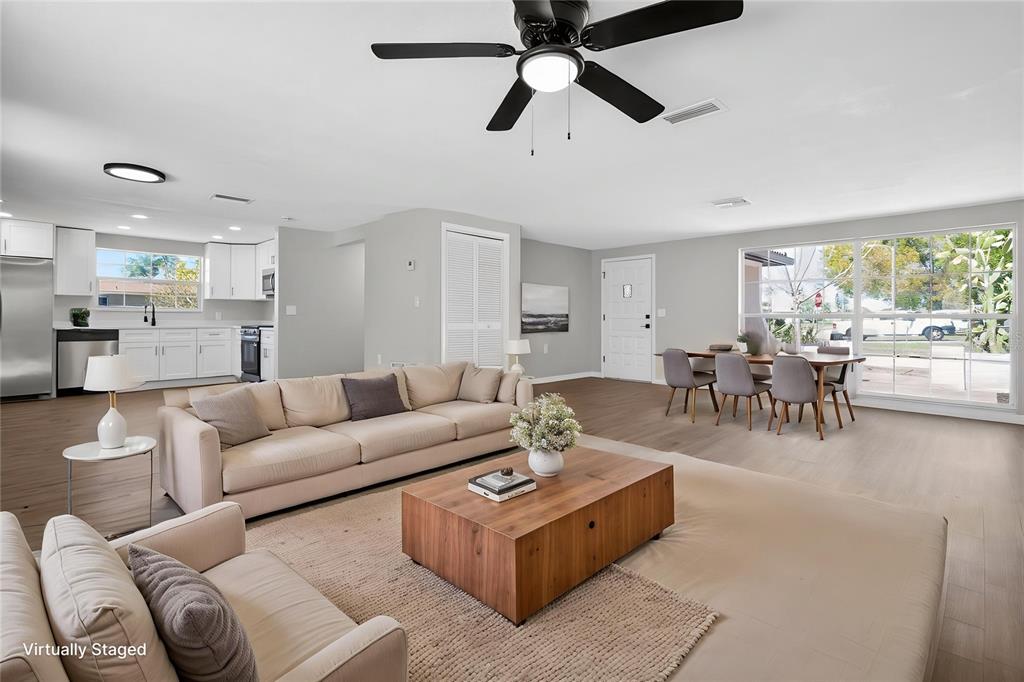 This open-concept living and dining area features light wood flooring, a ceiling fan, and white cabinetry — 3206 PINON DRIVE, HOLIDAY, FL