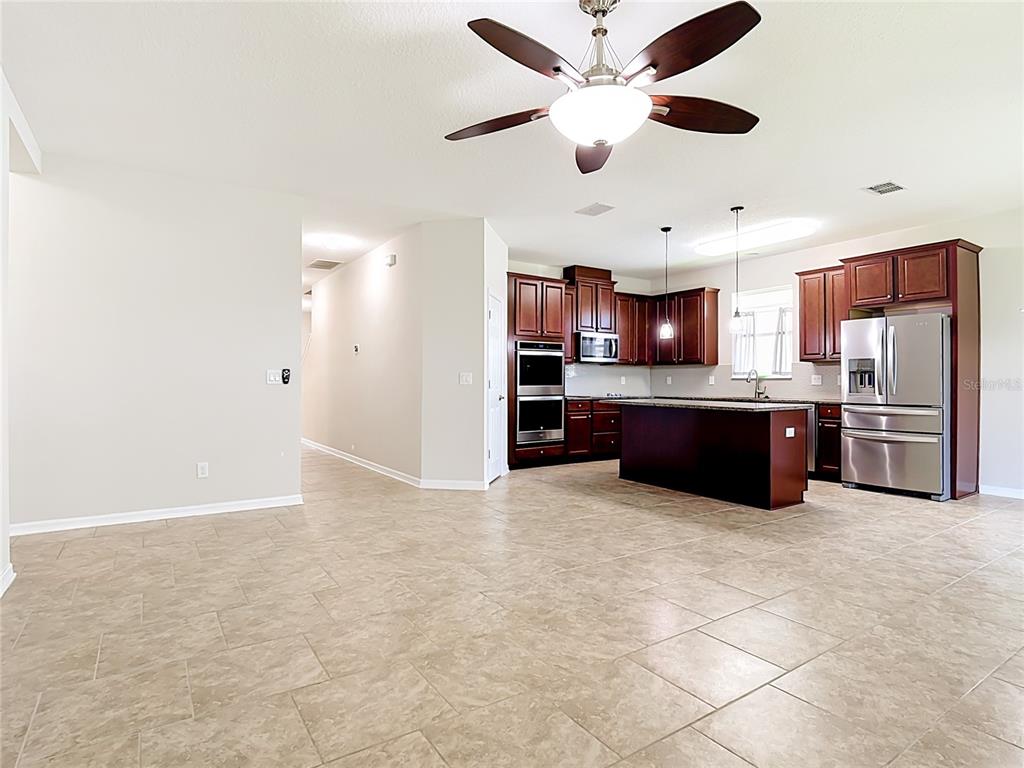 An open-concept kitchen with dark wood cabinets, stainless steel appliances, and tile flooring — 2687 GASPIRILLA CIRCLE, KISSIMMEE, FL