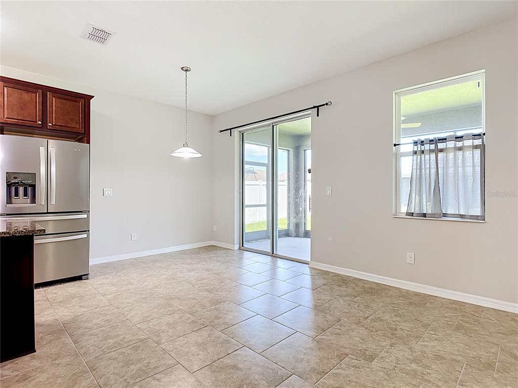 A kitchen dining area features tile flooring, stainless steel appliances, and a sliding glass door — 2687 GASPIRILLA CIRCLE, KISSIMMEE, FL