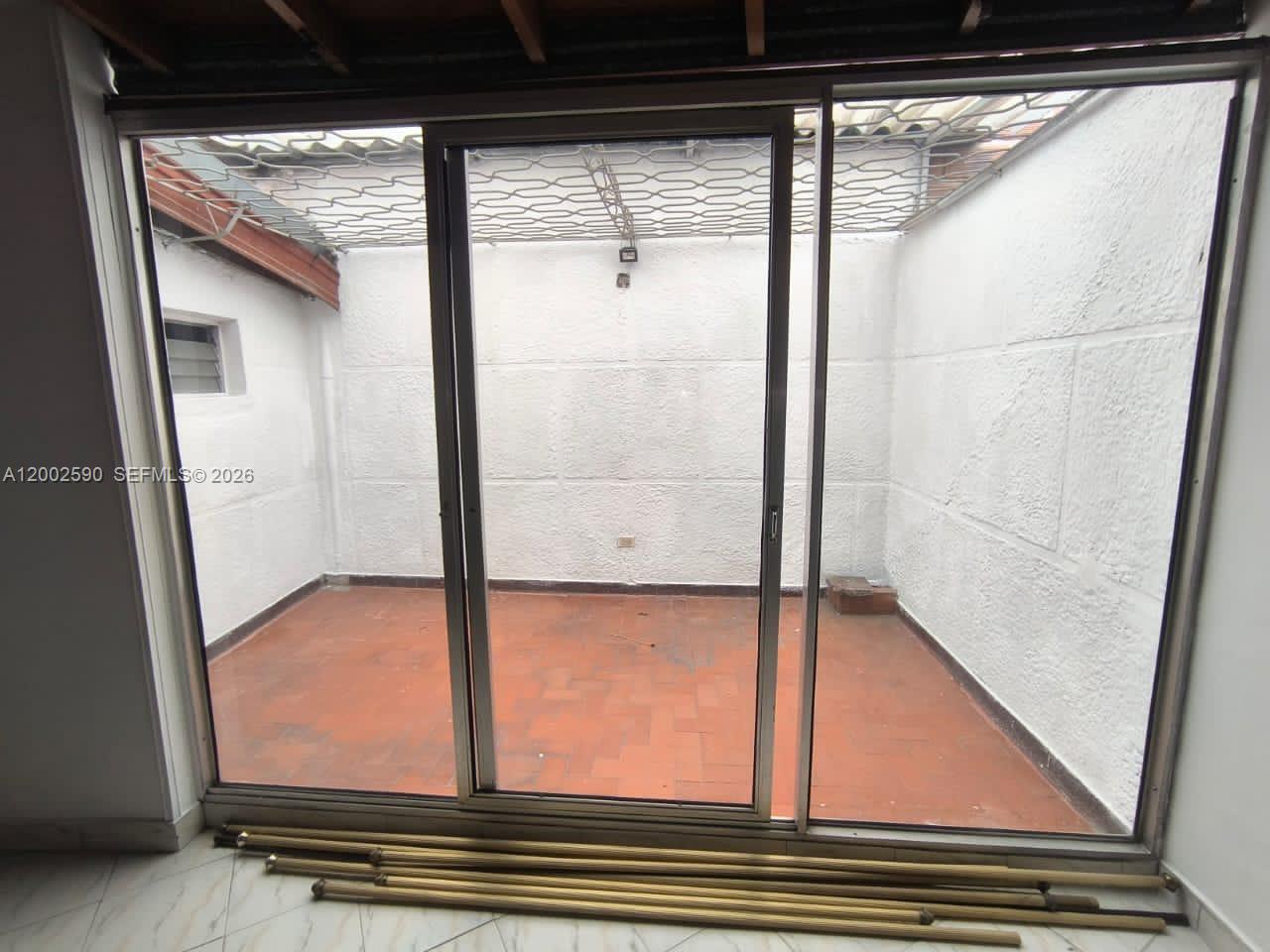 A sliding glass door opens onto a small, enclosed patio with terracotta tile flooring — Cra. 79B 54-15 Barrio los Colores, FL, FL