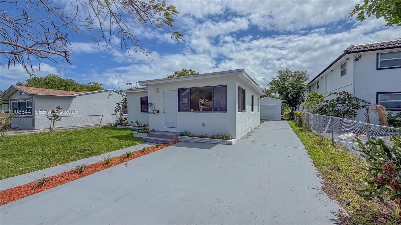 A white single-story house features a front driveway, a detached garage, and a chain-link fence — 2462 Johnson St, Hollywood FL 33020, HOLLYWOOD, FL