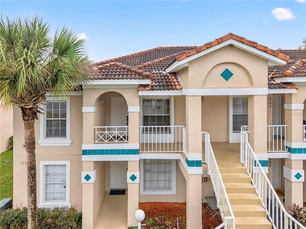 A two-story stucco apartment building features a tiled roof, exterior staircases, and balconies — 13917 TIMBERLAND DRIVE UNIT 201, ORLANDO, FL