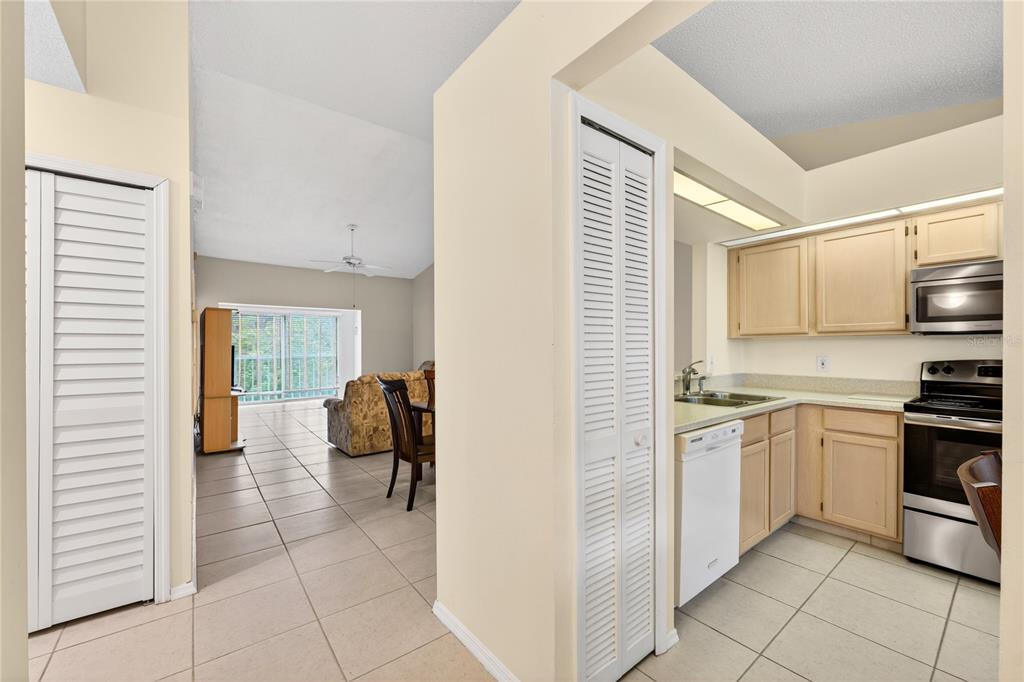 A view from a tiled hallway looking into a kitchen and a living area — 13917 TIMBERLAND DRIVE UNIT 201, ORLANDO, FL