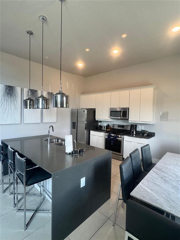 A modern kitchen features a large gray island, white cabinetry, and stainless steel appliances — 7770 SANDY RIDGE DRIVE UNIT 210, REUNION, FL
