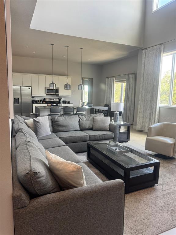 An open-concept living room features a large gray sectional sofa and a modern kitchen — 7770 SANDY RIDGE DRIVE UNIT 210, REUNION, FL