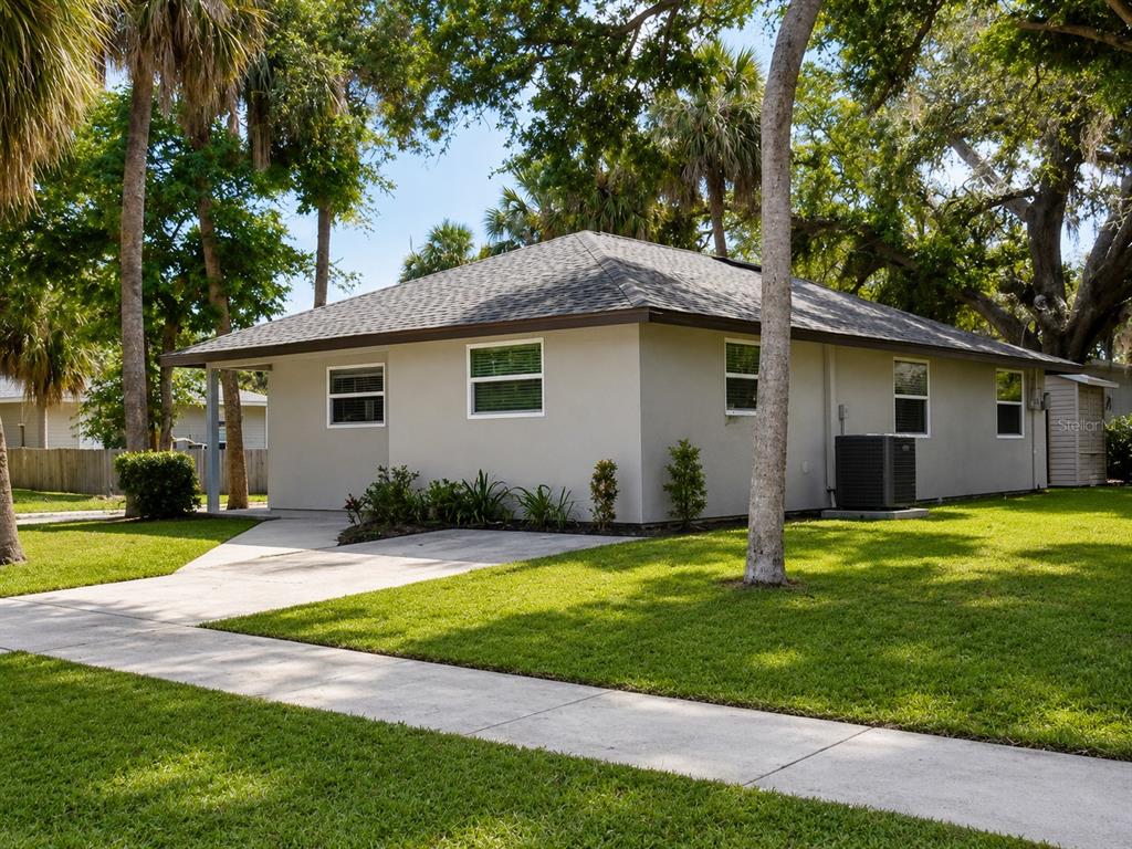 A single-story house with a light-colored exterior and a hip roof sits on a lawn — 3058 PALMADELIA AVENUE, SARASOTA, FL