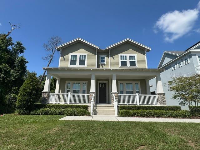 A two-story house with light green siding features a front porch and white railings — 7573 ESTUARY LAKE LOOP, CELEBRATION, FL