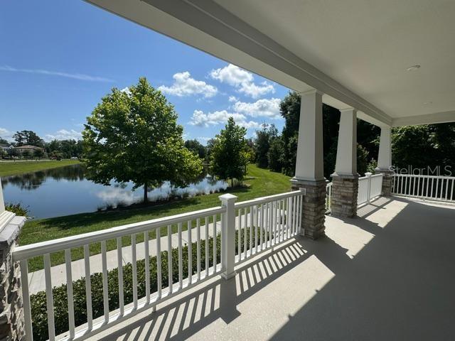 A covered porch with white railings overlooks a pond and green landscape — 7573 ESTUARY LAKE LOOP, CELEBRATION, FL