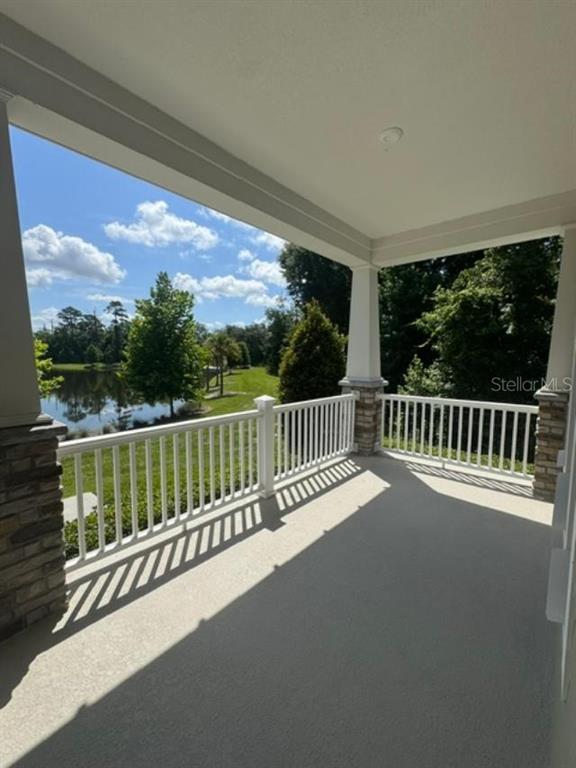 A covered porch with white railings overlooks a grassy yard and a small lake — 7573 ESTUARY LAKE LOOP, CELEBRATION, FL