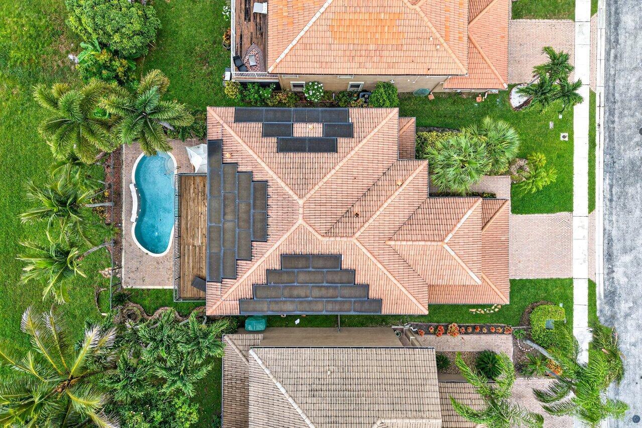 An aerial view shows a house with solar panels on the roof and a pool — 5347 Island Gypsy Drive, FL 33463, FL