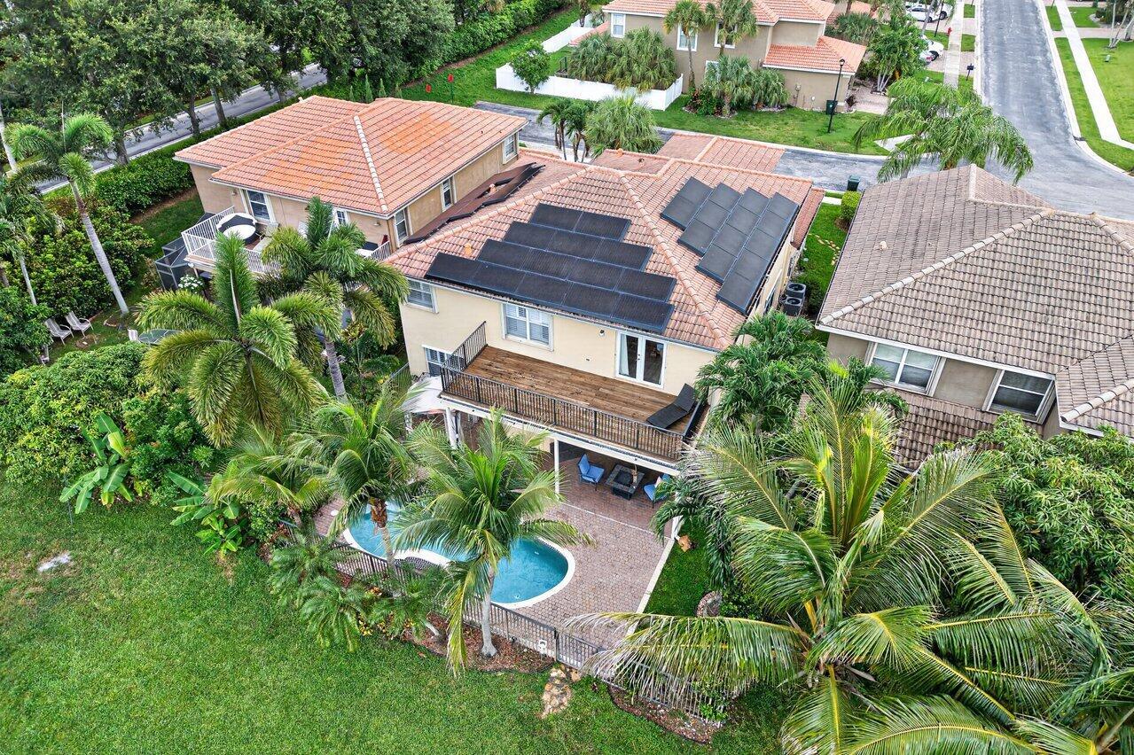An aerial view of a two-story house with solar panels, a balcony, and a pool — 5347 Island Gypsy Drive, FL 33463, FL