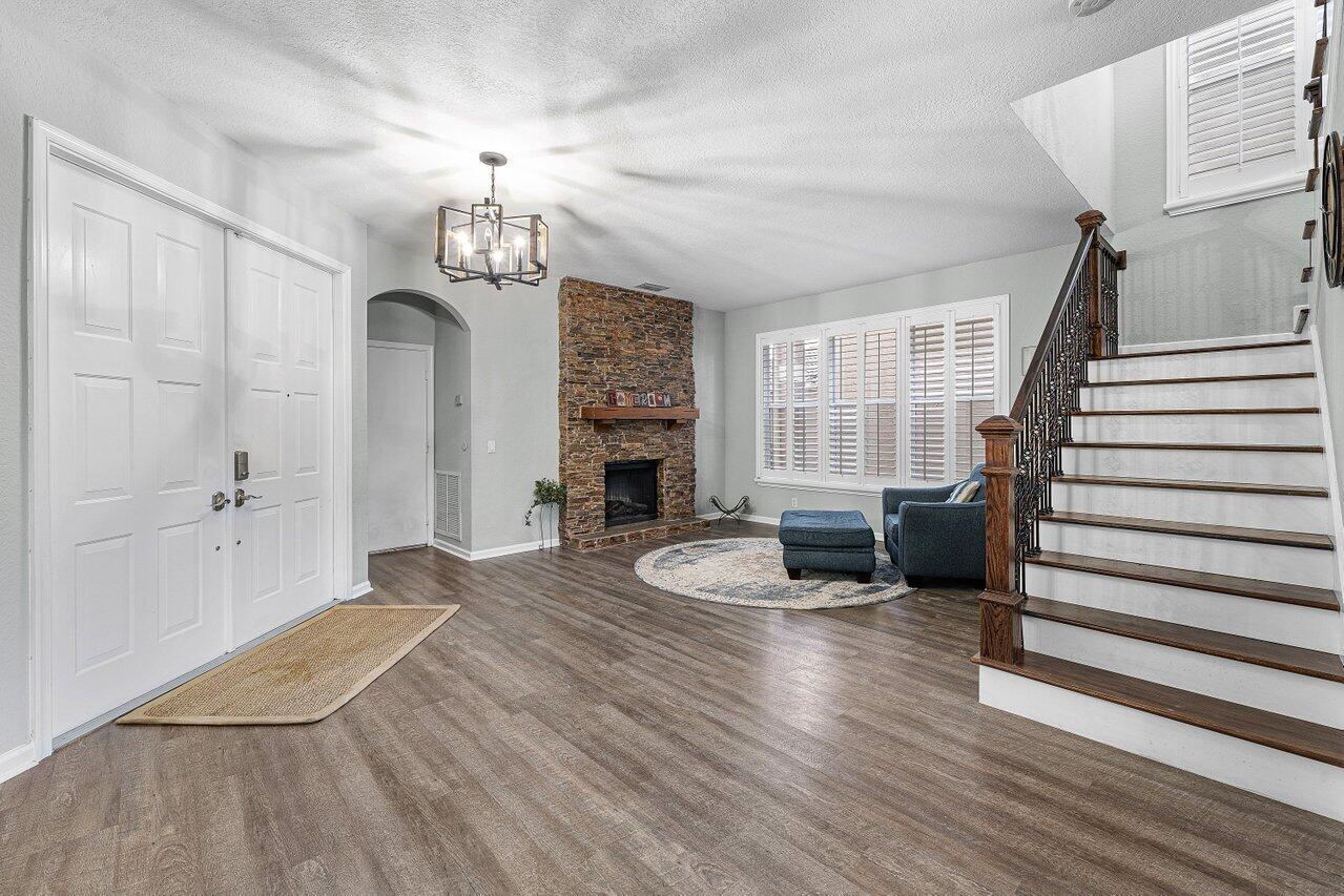 A foyer with wood-look flooring, a stone fireplace, and a staircase with a dark railing — 5347 Island Gypsy Drive, FL 33463, FL