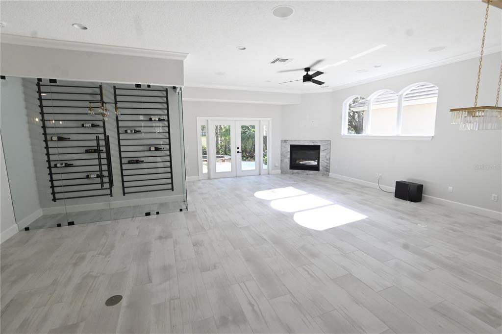 A spacious living room features light wood-look tile floors, a glass-enclosed wine rack, and a fireplace — 6119 FOXFIELD COURT, WINDERMERE, FL