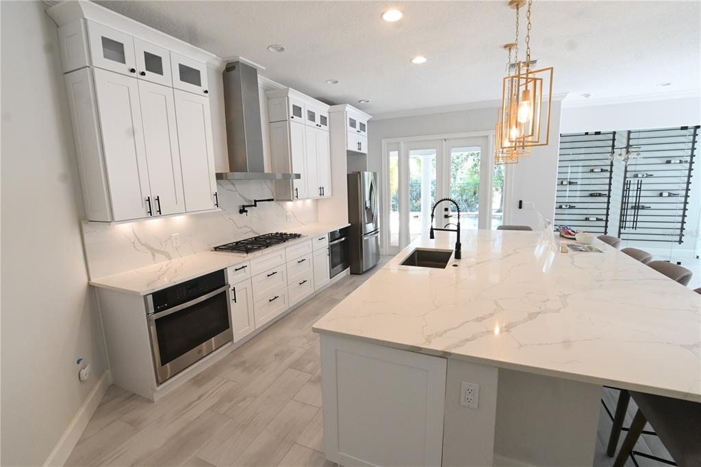 A modern kitchen features white cabinetry, marble-style countertops, stainless steel appliances, and a large island — 6119 FOXFIELD COURT, WINDERMERE, FL