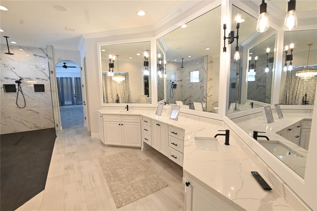 A modern bathroom features a double vanity with white cabinets, marble countertops, and large mirrors — 6119 FOXFIELD COURT, WINDERMERE, FL