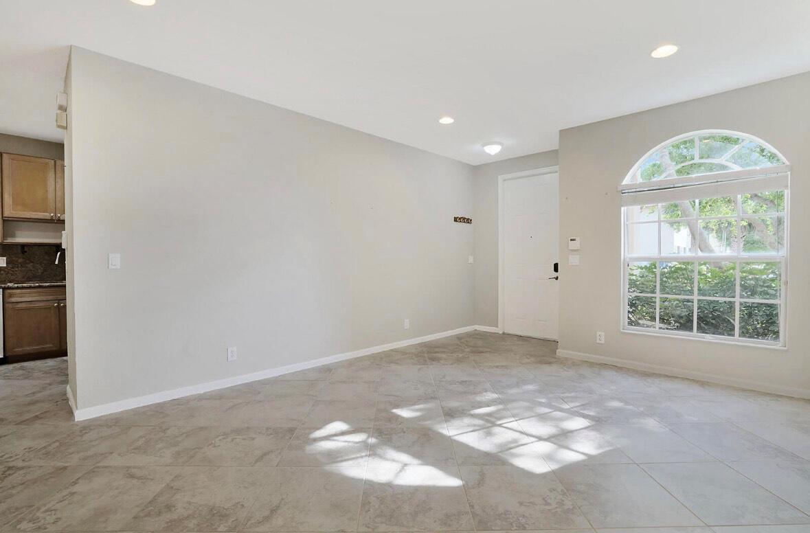 An empty room with light-colored tile flooring, a large arched window, and a white door — 16097 Poppyseed Circle # 1905, Delray Beach FL 33484, DELRAY BEACH, FL