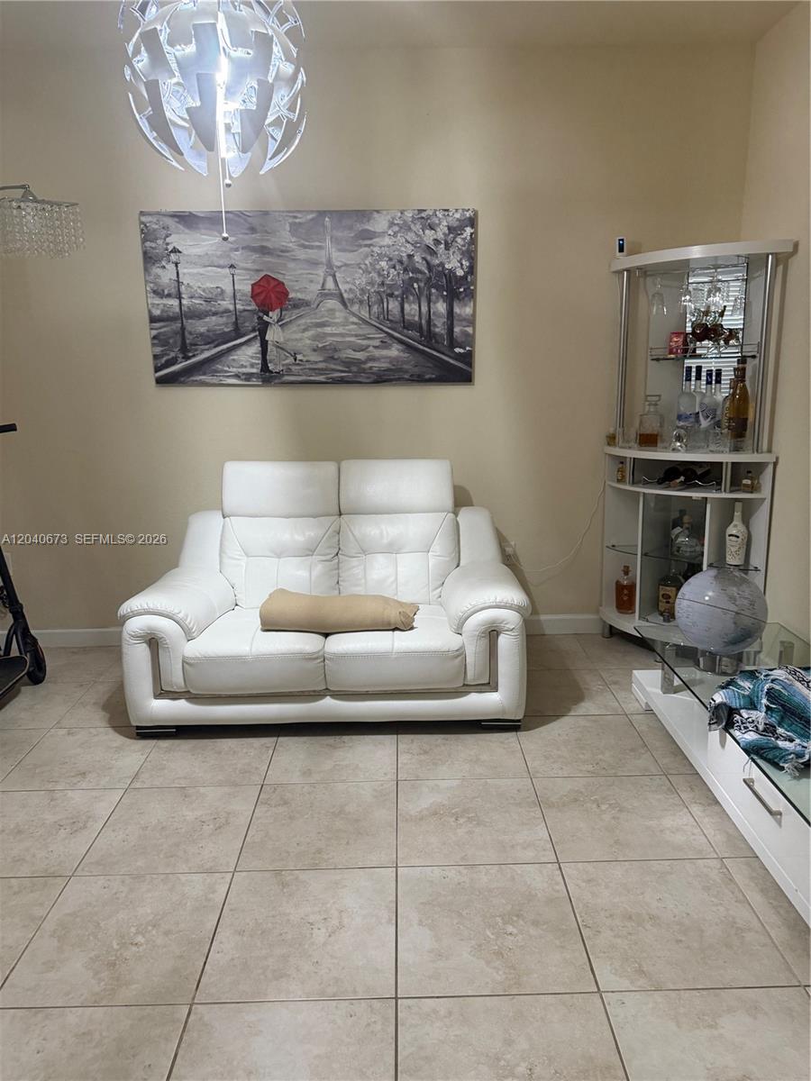 A living room features a white leather loveseat, a corner bar cabinet, and wall art — 8929 W 35th Way, Hialeah FL 33018, HIALEAH, FL