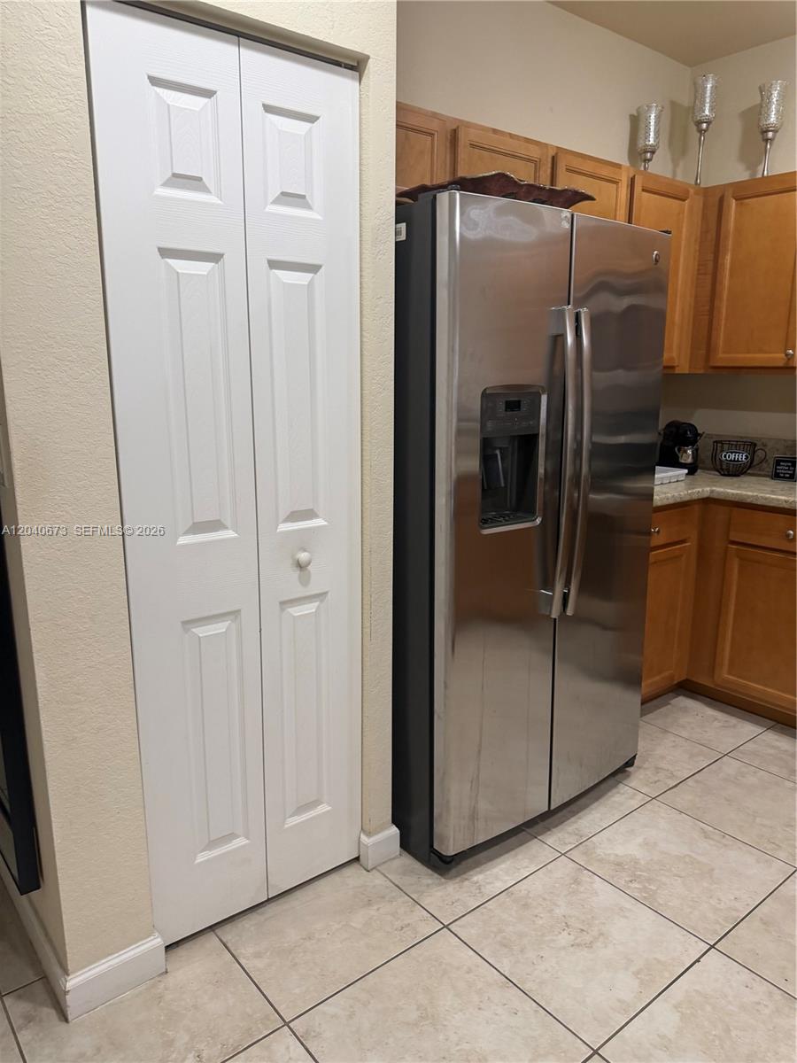 A kitchen features a stainless steel refrigerator next to a white bi-fold closet door — 8929 W 35th Way, Hialeah FL 33018, HIALEAH, FL