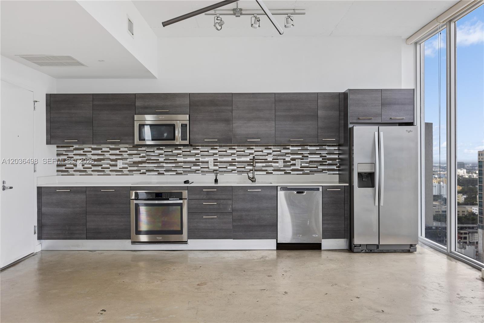 A modern kitchen features dark wood cabinetry, stainless steel appliances, and a tiled backsplash — 151 SE 1st St # 3202, Miami FL 33131, MIAMI, FL
