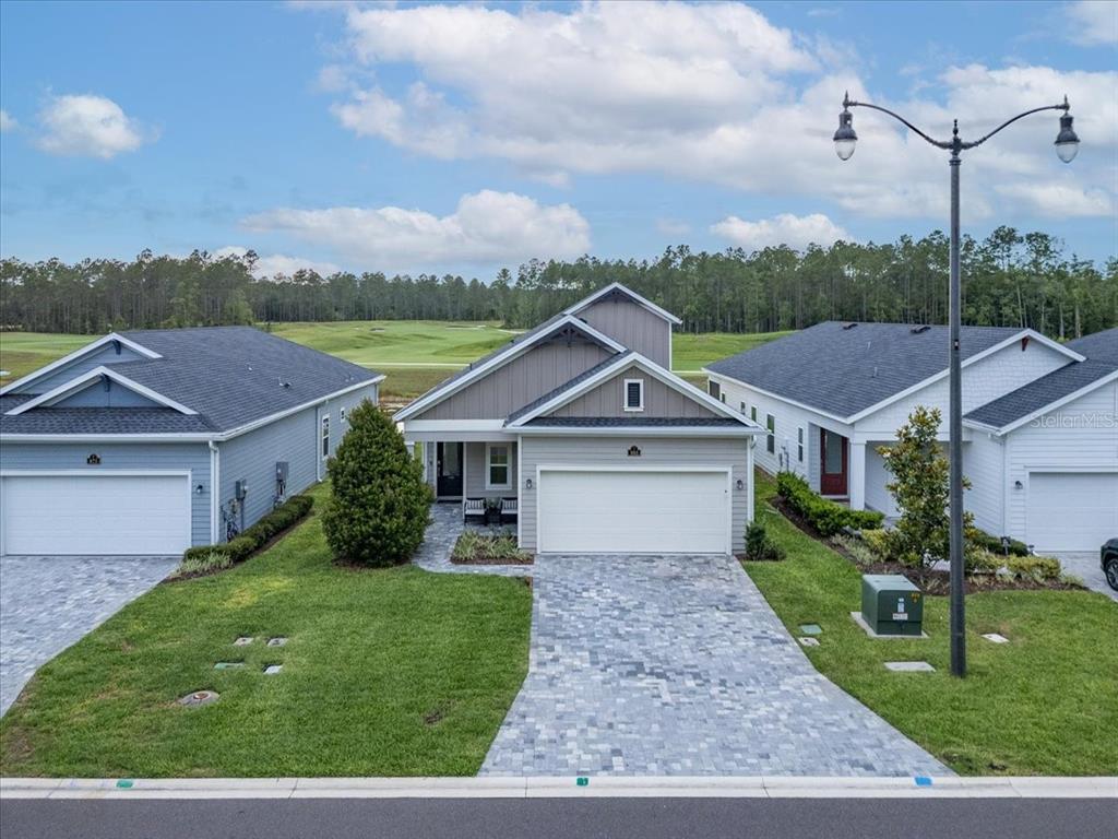 An exterior view of a single-story house with a paved driveway and a golf course view — 883 STILLWATER BOULEVARD, ST JOHNS, FL