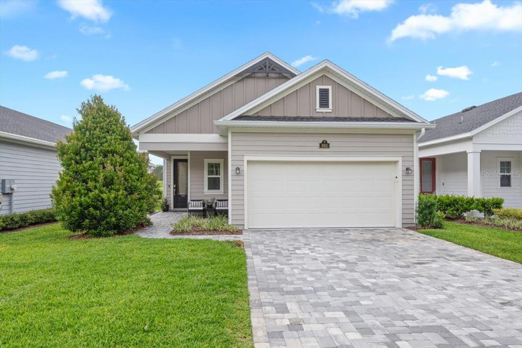 A single-story house with beige siding, a two-car garage, and a paved driveway — 883 STILLWATER BOULEVARD, ST JOHNS, FL