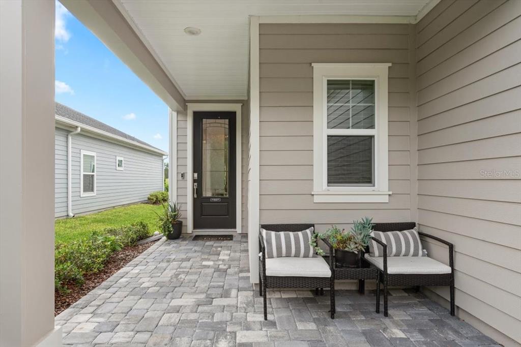 A covered front porch features a paved floor, a dark front door, and two chairs — 883 STILLWATER BOULEVARD, ST JOHNS, FL