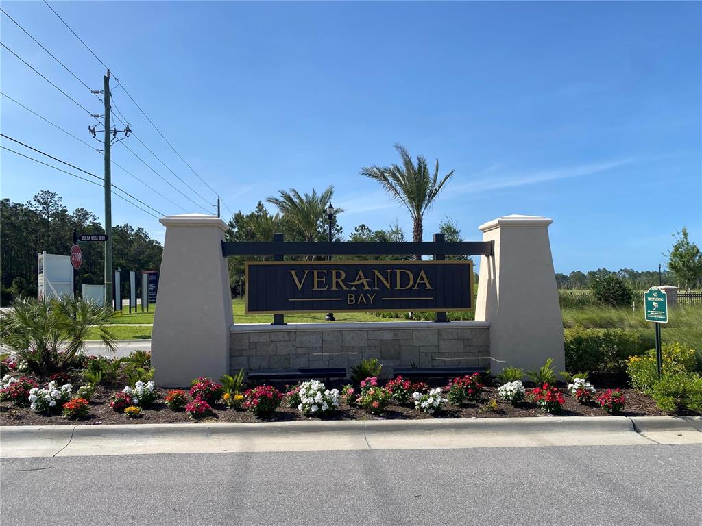 A stone and stucco monument sign for Veranda Bay stands beside a paved road — 46 CORONADO ROAD UNIT N/A, FLAGLER BEACH, FL