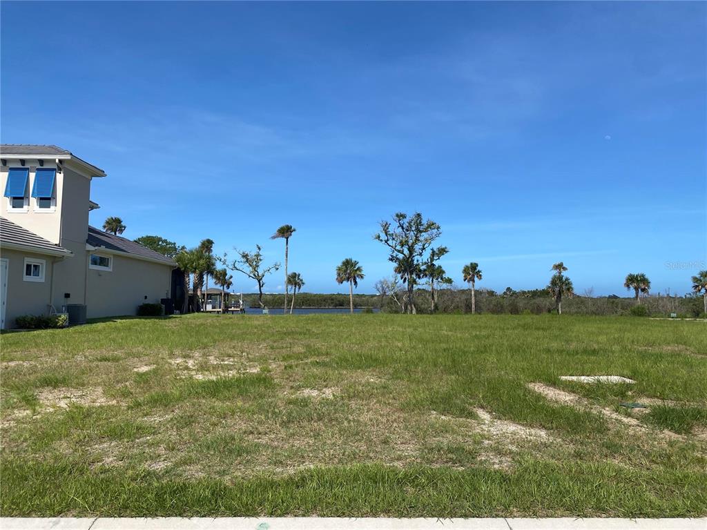 A vacant grassy lot sits next to a house with a view of the water — 46 CORONADO ROAD UNIT N/A, FLAGLER BEACH, FL