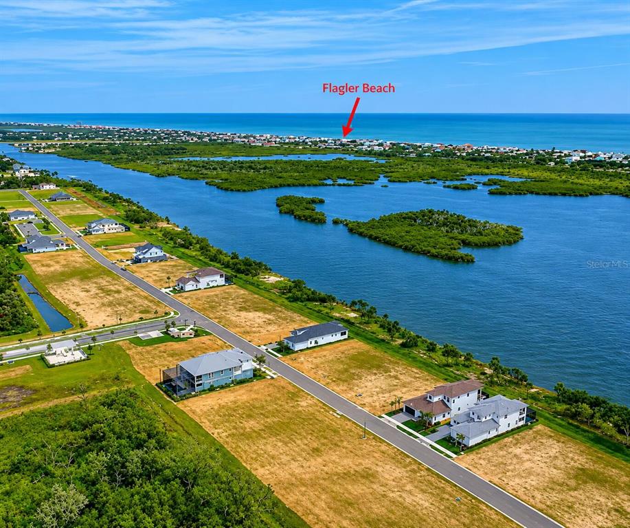 An aerial view shows a coastal neighborhood with houses, undeveloped lots, and a large waterway — 46 CORONADO ROAD UNIT N/A, FLAGLER BEACH, FL