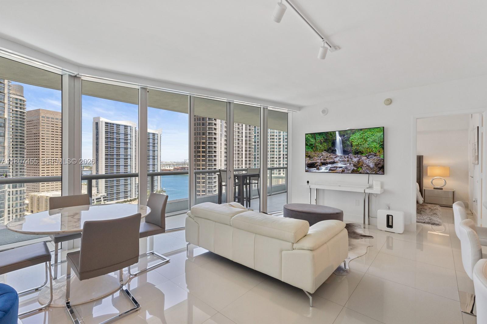 A modern living and dining area features floor-to-ceiling windows with city and water views — 495 Brickell Ave # 2304, Miami FL 33131, MIAMI, FL