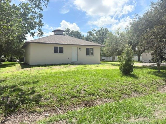 A single-story house with a hip roof and a small cupola sits on a lawn — 607 2ND STREET NW, RUSKIN, FL