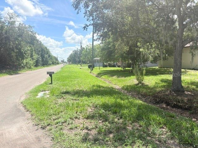 A rural road runs alongside a grassy yard with mature trees and a mailbox — 607 2ND STREET NW, RUSKIN, FL