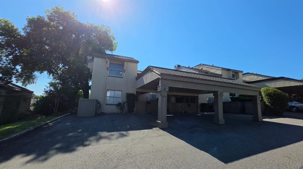 A two-story building exterior features a large covered carport and a paved parking area — 550 WINDMEADOWS STREET UNIT 550, ALTAMONTE SPRINGS, FL