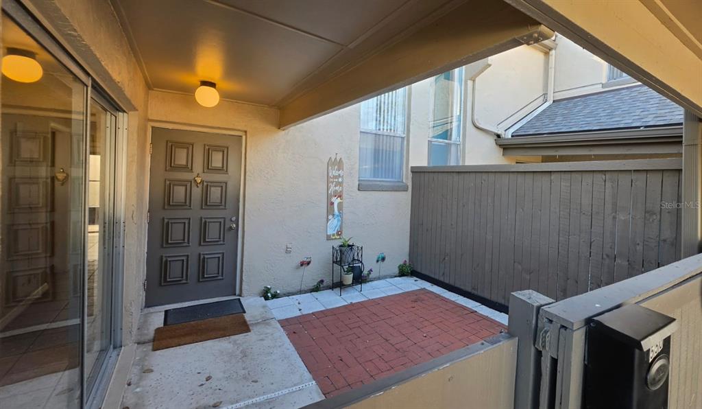 A covered entryway features a gray front door, a brick patio, and a privacy fence — 550 WINDMEADOWS STREET UNIT 550, ALTAMONTE SPRINGS, FL