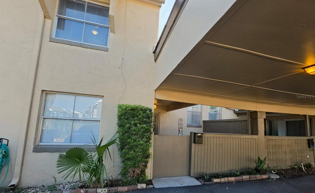 An exterior view of a two-story building with a covered carport and a gated entrance — 550 WINDMEADOWS STREET UNIT 550, ALTAMONTE SPRINGS, FL