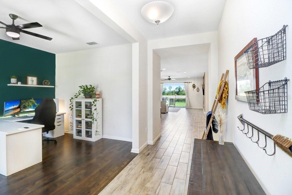 A home office with dark wood floors opens into a hallway with light tile flooring — 11520 BLUE WOODS DRIVE, RIVERVIEW, FL