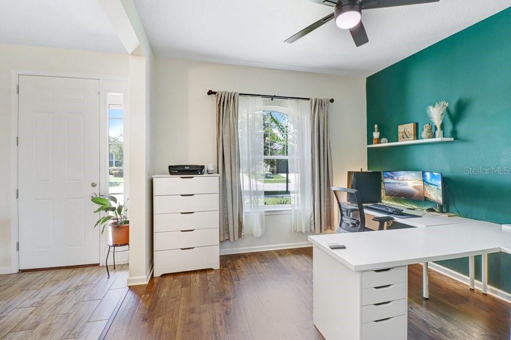 A home office features a white desk, a tall dresser, and a teal accent wall — 11520 BLUE WOODS DRIVE, RIVERVIEW, FL