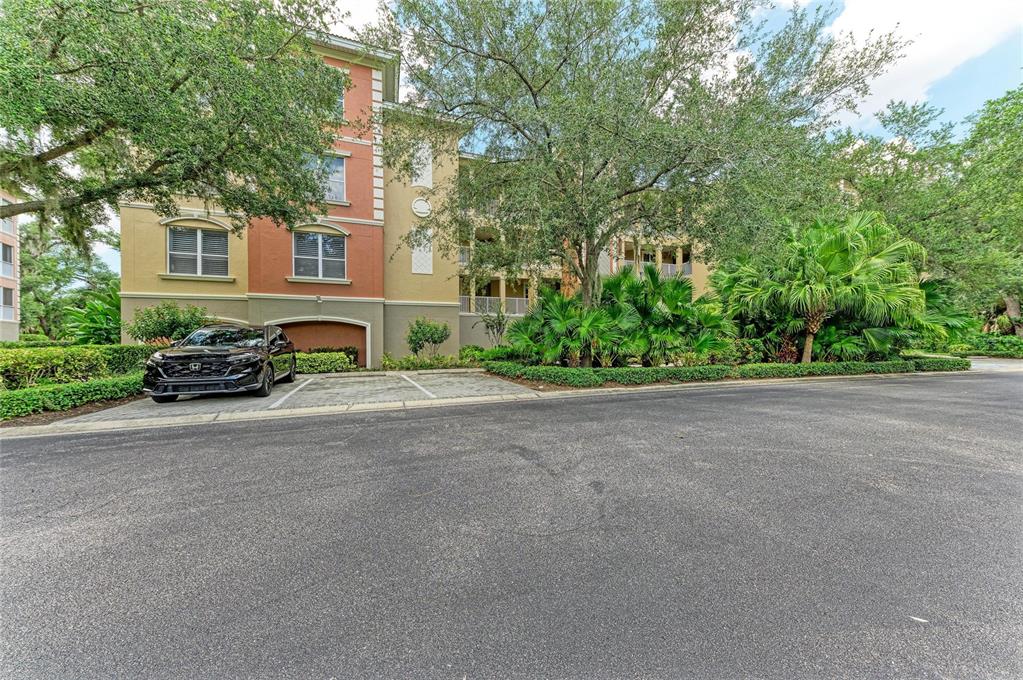 A multi-story apartment building with a parking space and a black car in front — 5200 MANORWOOD DRIVE UNIT 2D, SARASOTA, FL