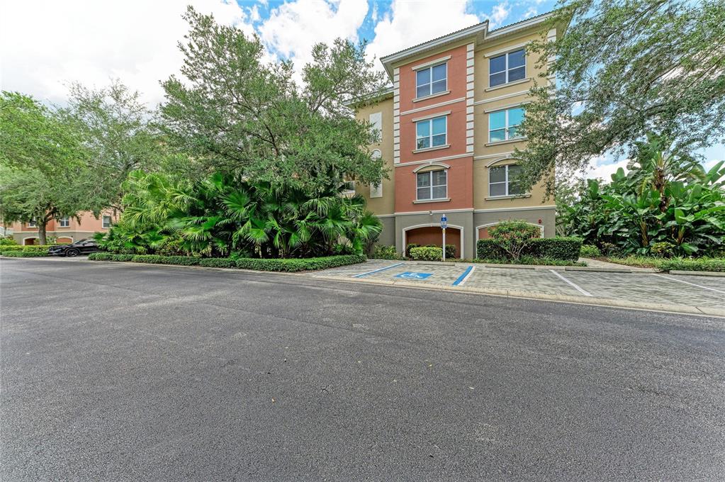 A multi-story apartment building features a tan and orange facade with a handicap parking space — 5200 MANORWOOD DRIVE UNIT 2D, SARASOTA, FL