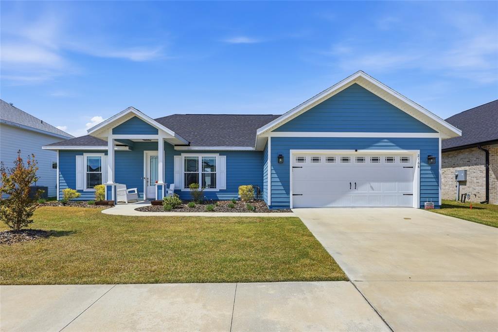 A blue single-story house with a white garage door and a covered front entryway — 2168 SW 245TH DRIVE, NEWBERRY, FL
