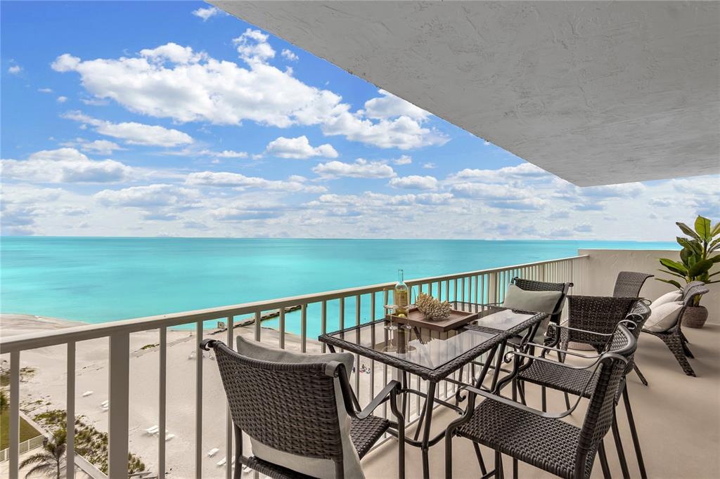 A balcony with outdoor furniture overlooks a sandy beach and the turquoise ocean — 2301 GULF OF MEXICO DRIVE UNIT 102N, LONGBOAT KEY, FL