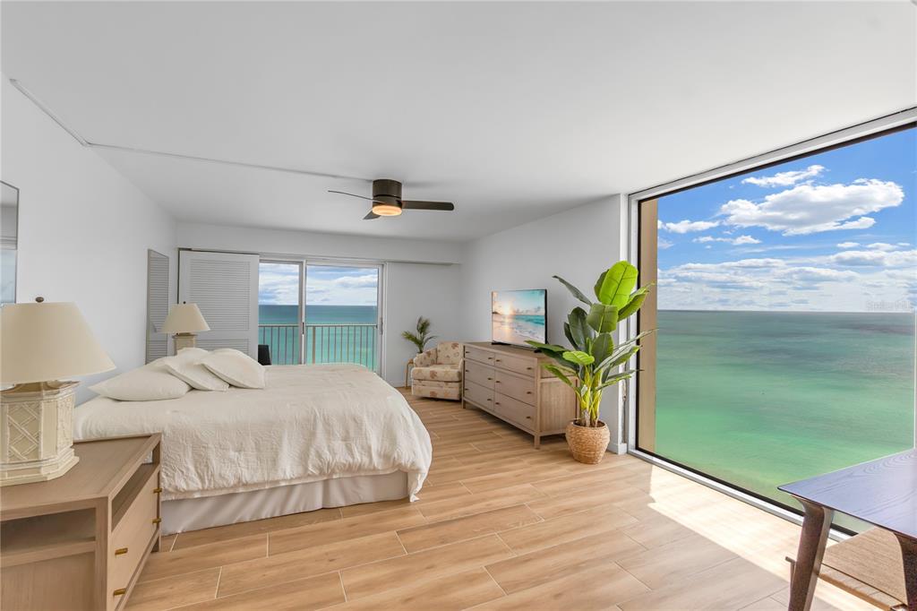 A bedroom with wood-look tile floors, a bed, and floor-to-ceiling windows overlooking the ocean — 2301 GULF OF MEXICO DRIVE UNIT 102N, LONGBOAT KEY, FL
