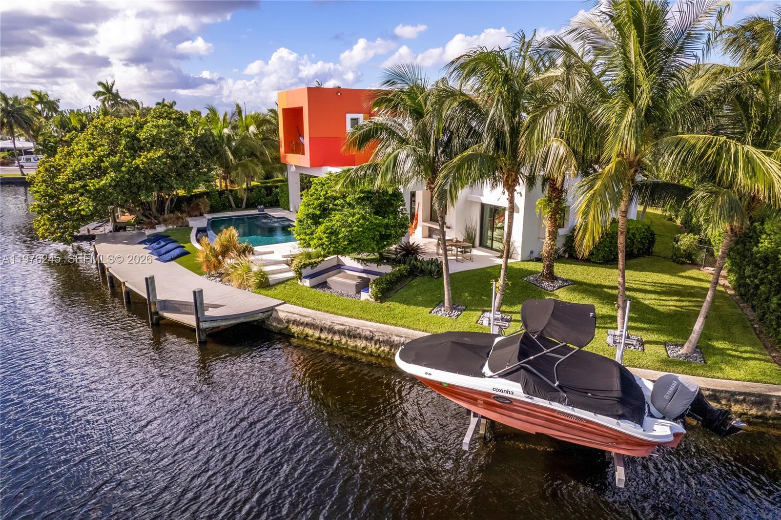An aerial view shows a modern house with an orange accent, pool, dock, and boat — 2101 NE 20th Ave, Wilton Manors FL 33305, WILTON MANORS, FL